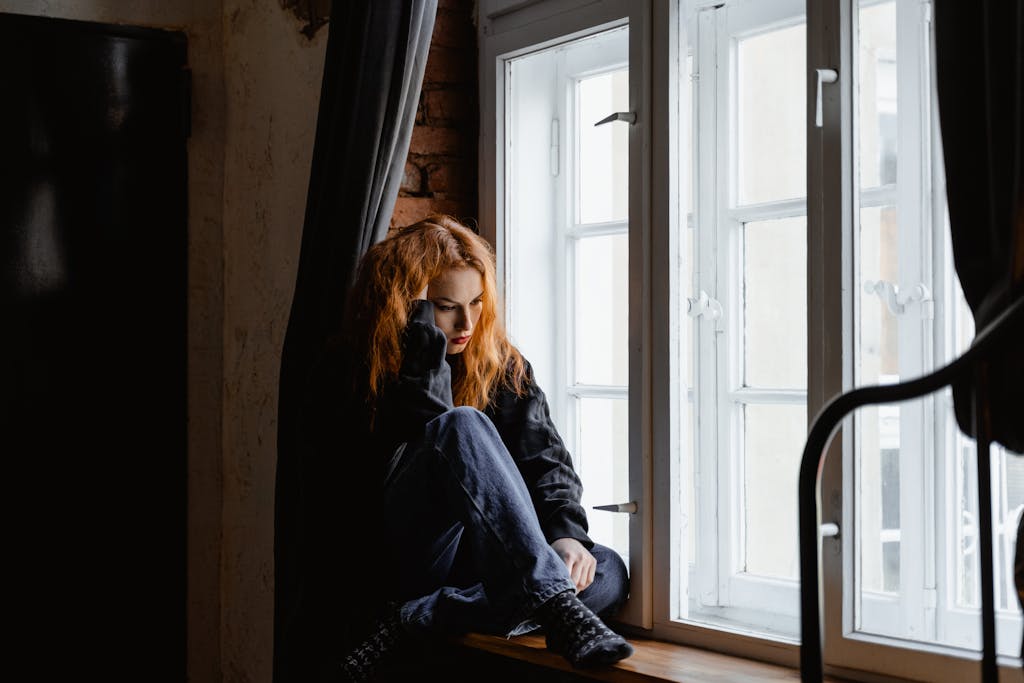 A woman sits by a window, lost in deep thoughts and moody light.  Your ready for a change in your career